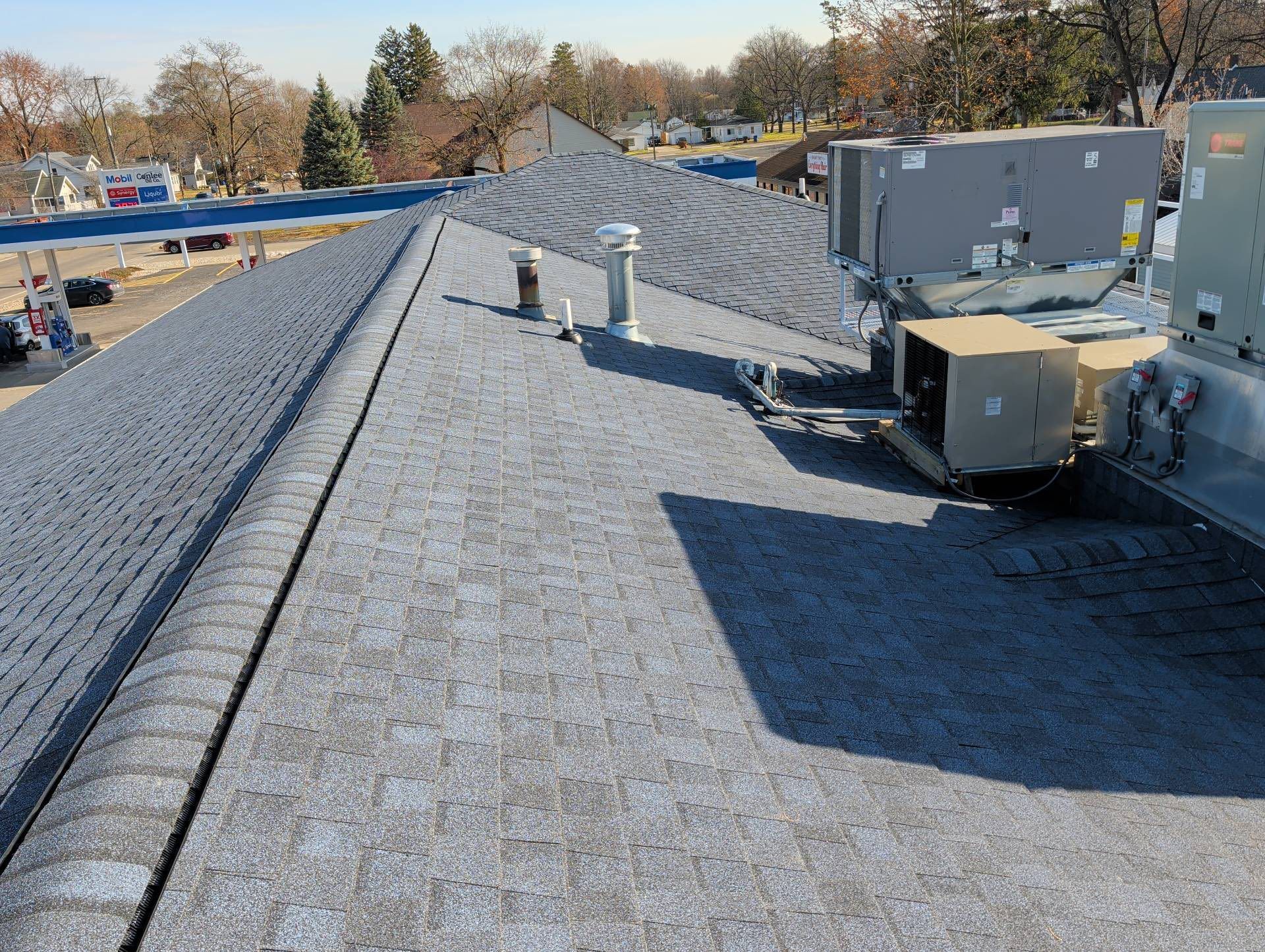 Flat gravel rooftop with HVAC units and vents under a clear sky.