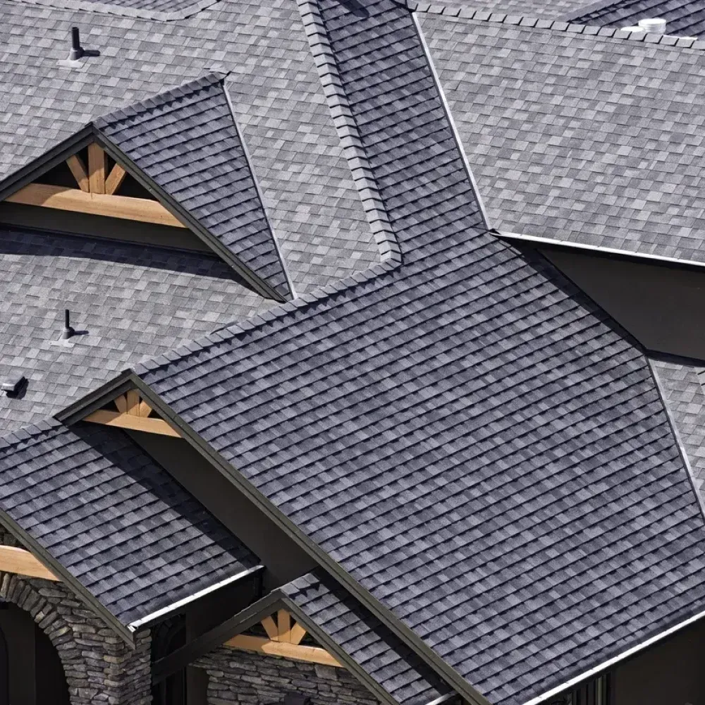 Aerial view of overlapping gray shingle roofs on a house under construction