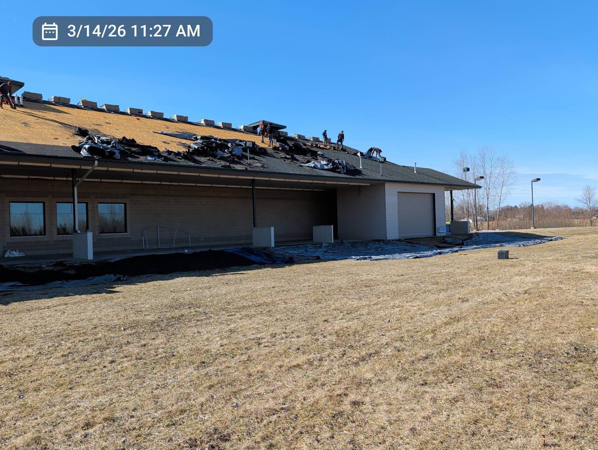 Damaged house with a collapsed roof in a dry, grassy field under a clear blue sky.