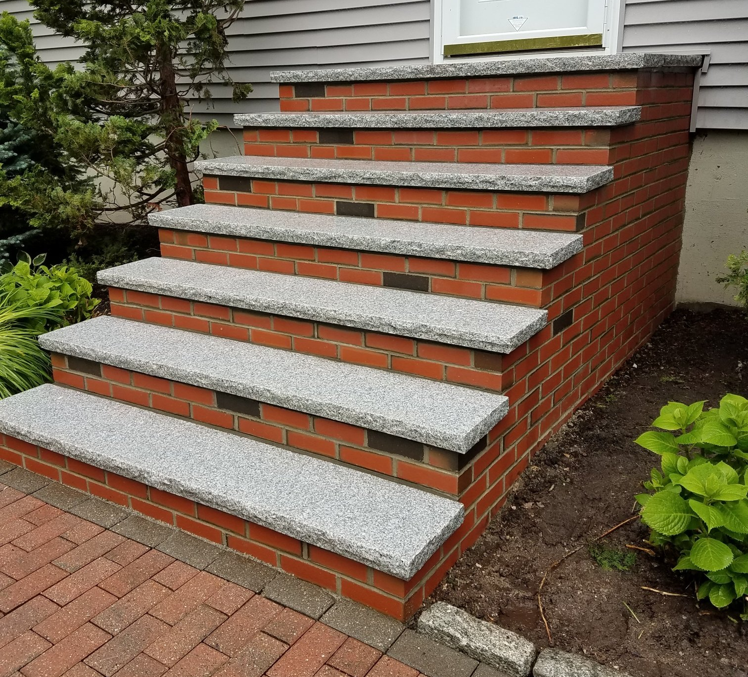 Brick steps with gray speckled treads leading to a white door.
