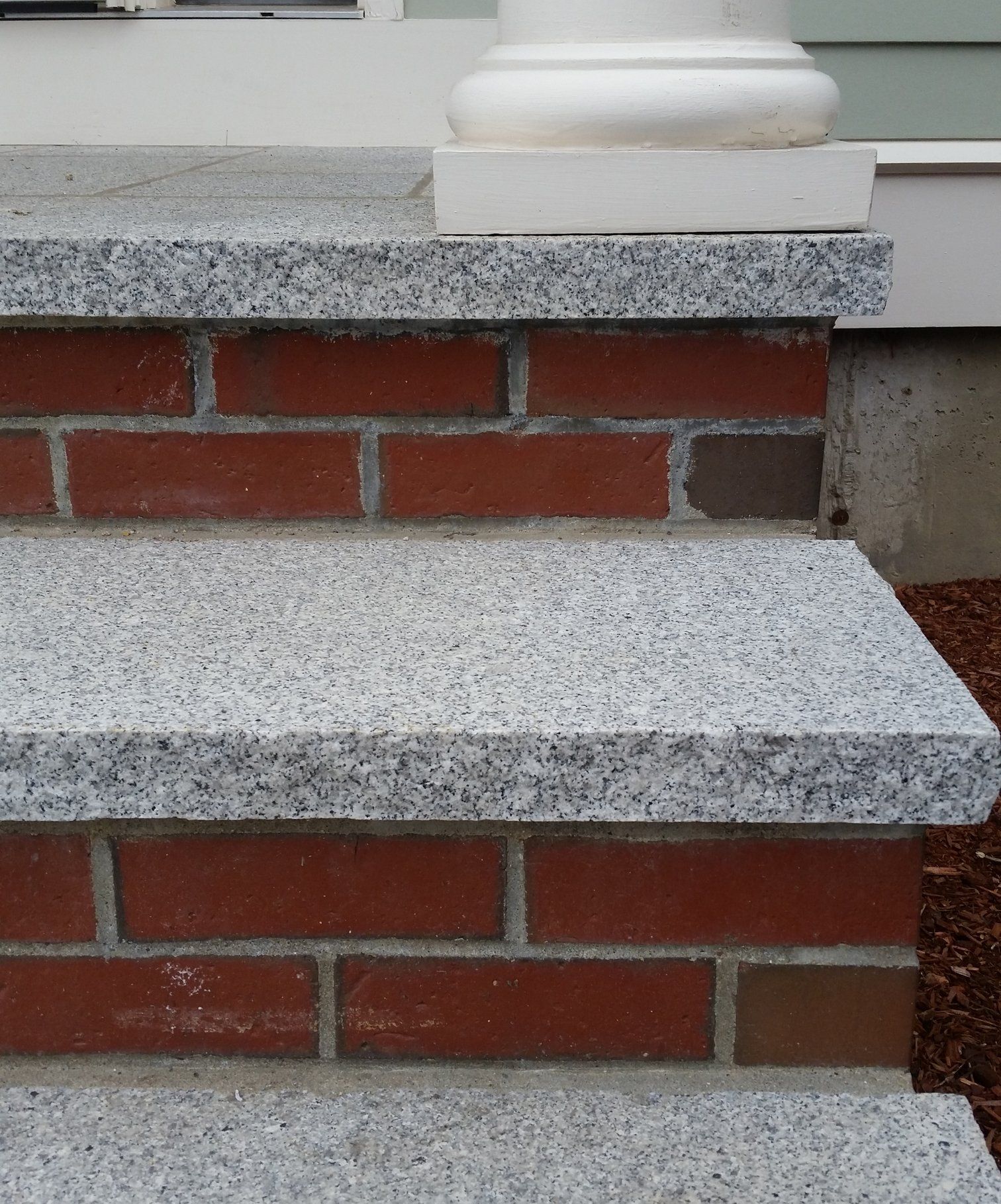 Brick steps with granite treads, leading up to a white column base.