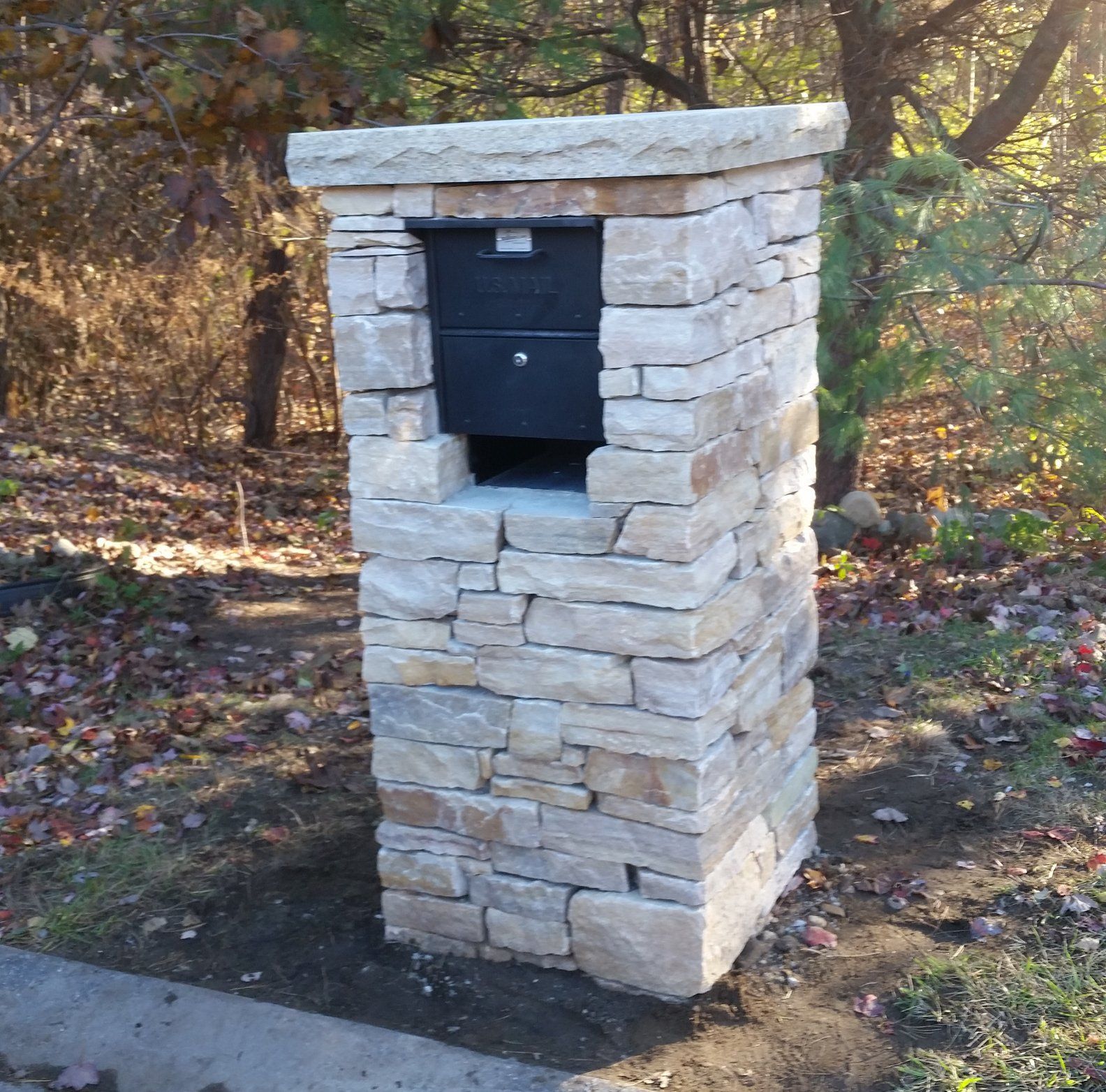 Stone mailbox pillar with black mailbox.