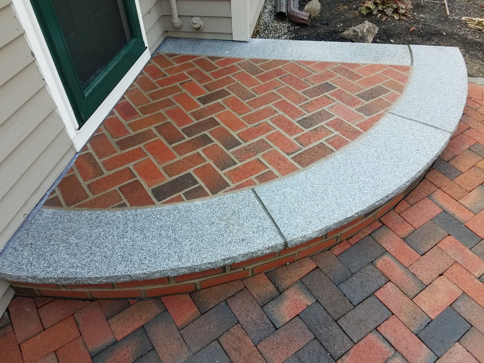 Brick entryway with curved granite border and herringbone pattern.
