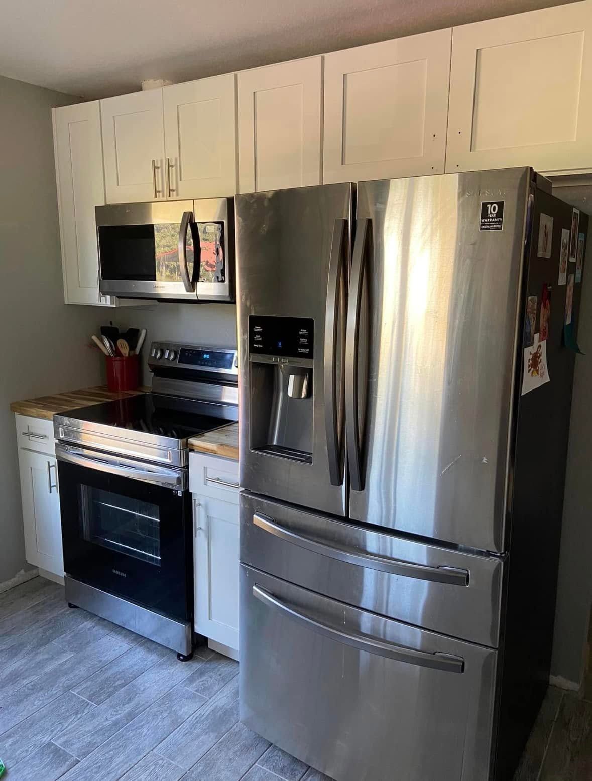 Modern kitchen with stainless steel refrigerator, stove, microwave, and white cabinets