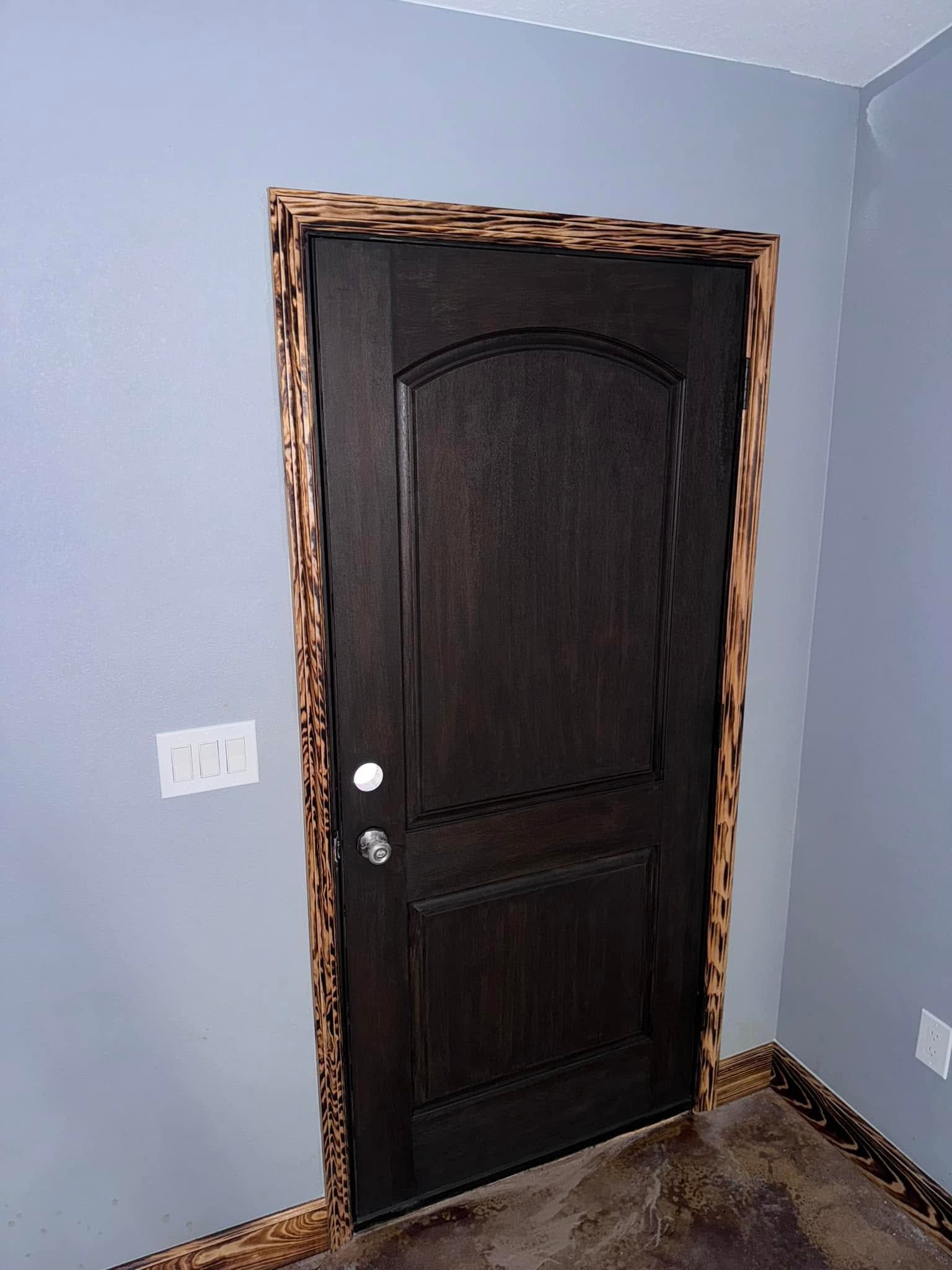 Dark wooden door with ornate trim in a light blue room