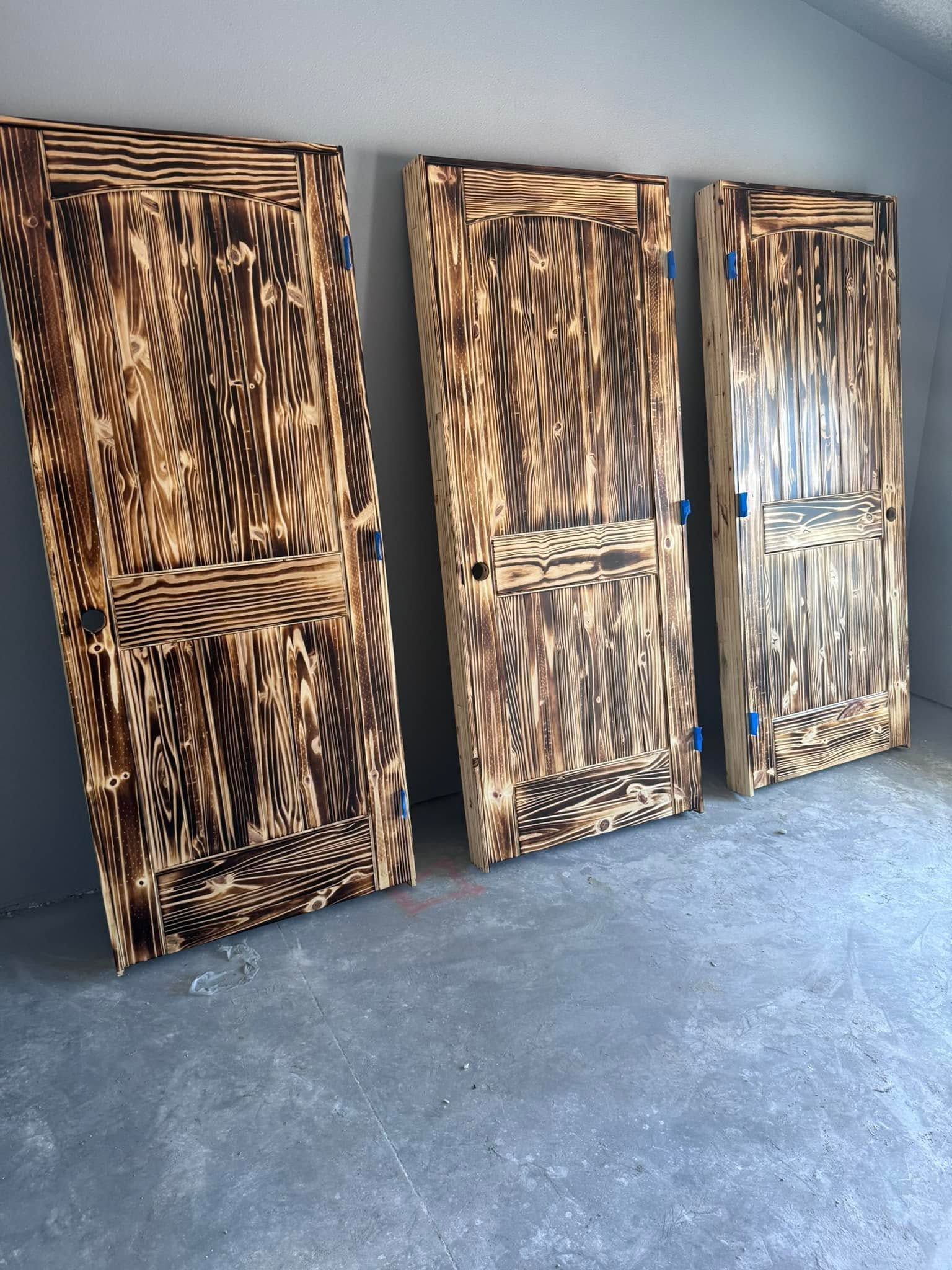 Three tall black-and-brown patterned cabinets leaning against a wall on a gray floor.