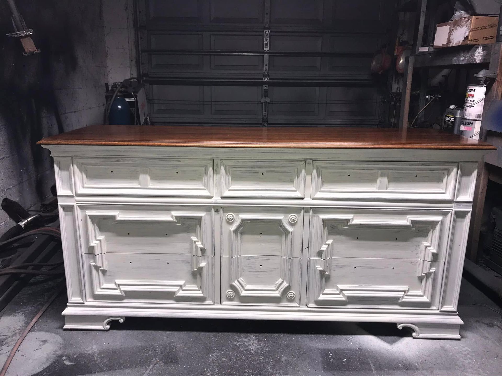 White vintage sideboard cabinet with wooden top in a garage or workshop setting