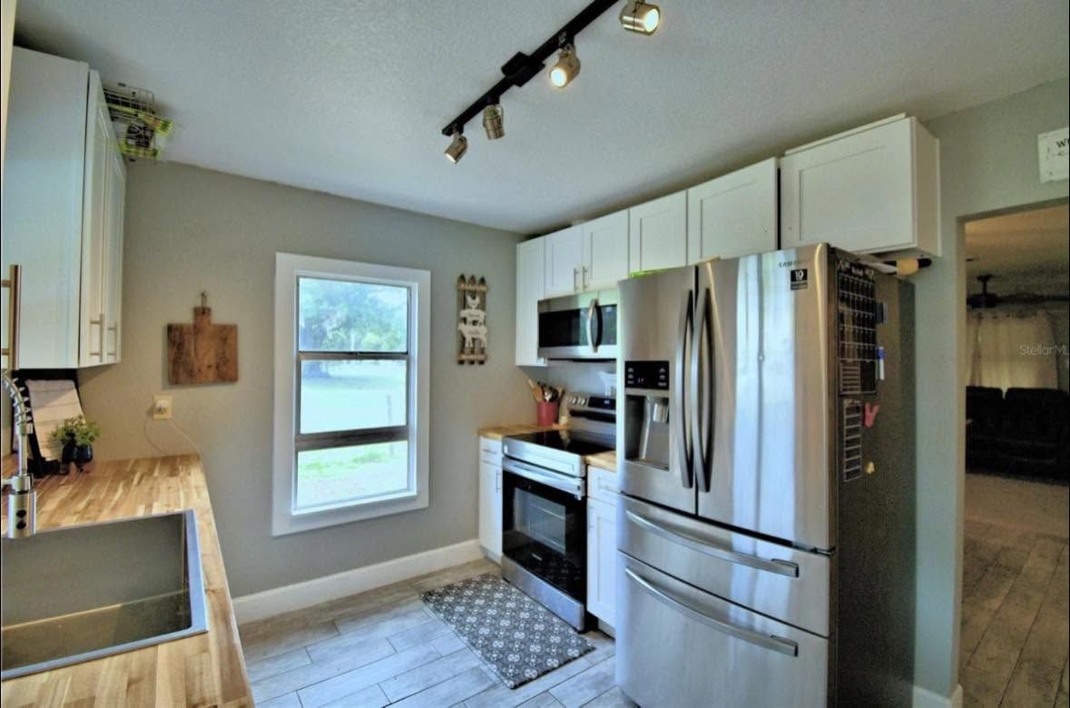 Modern kitchen with stainless steel appliances, white cabinets, and a window over the sink.