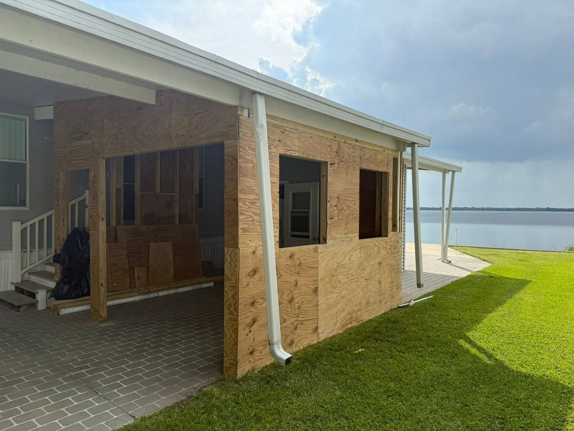 Beach house patio with brick walls, white columns, and a grassy yard overlooking the water
