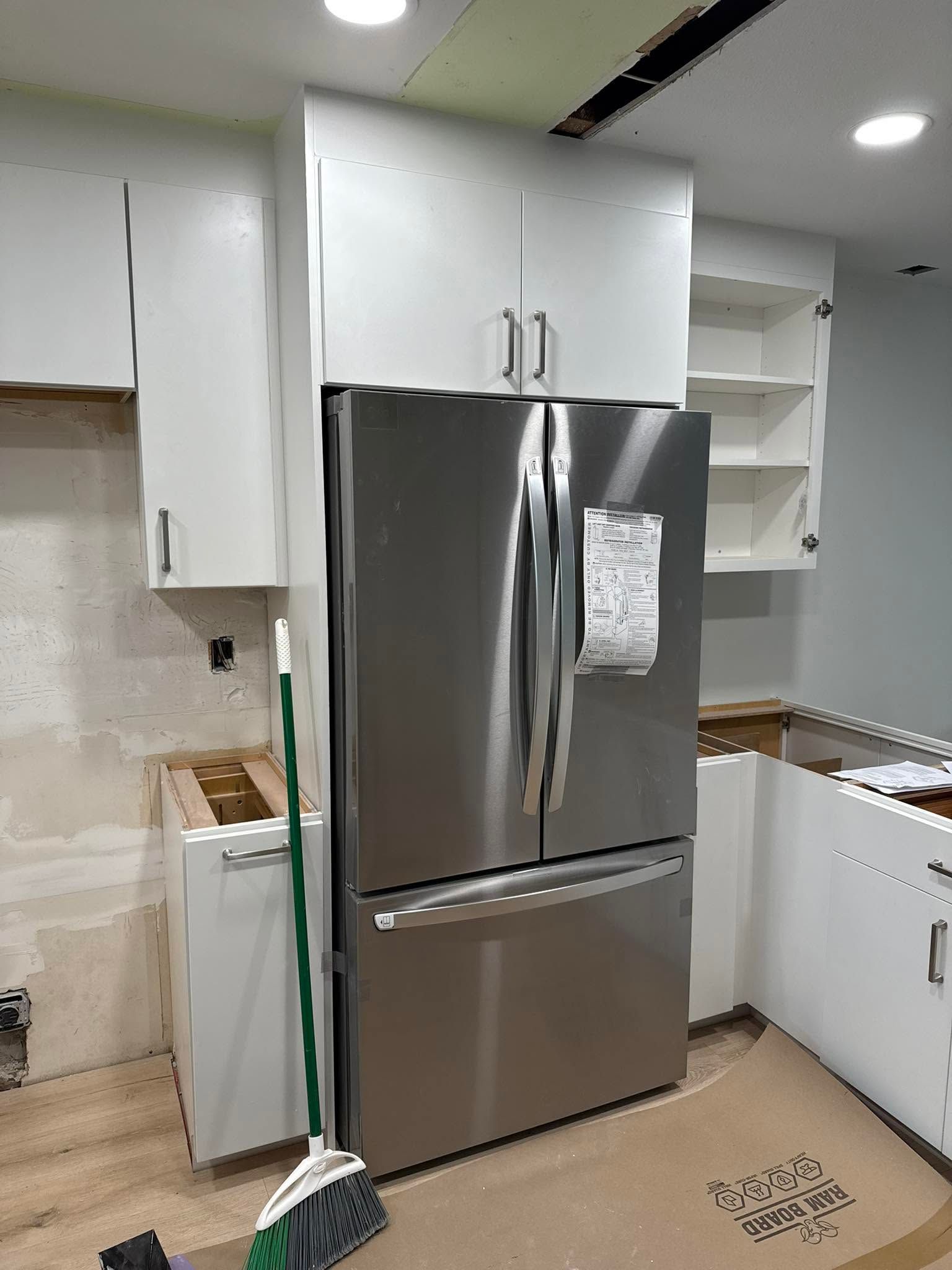 Kitchen with stainless steel refrigerator, white cabinets, and a white stove in a bright modern room
