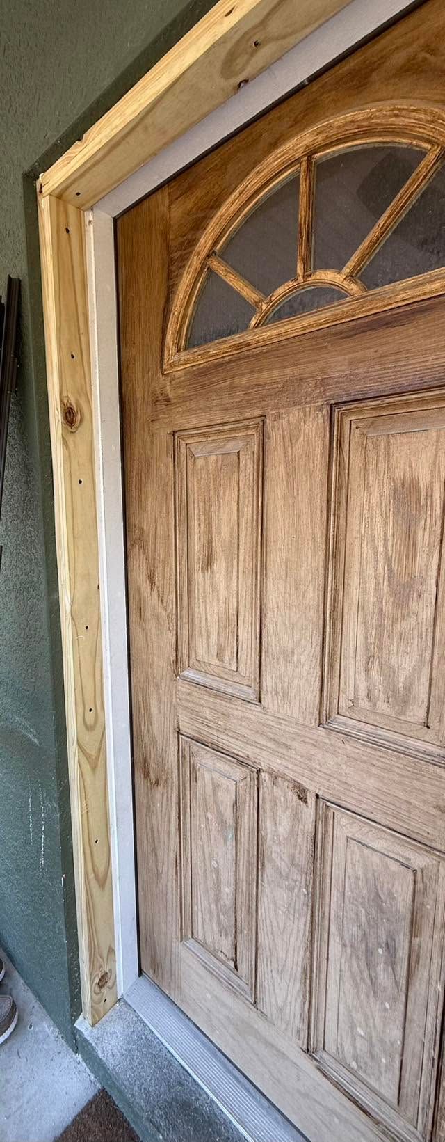 Wooden front door with a semicircular window and stone threshold at an entryway