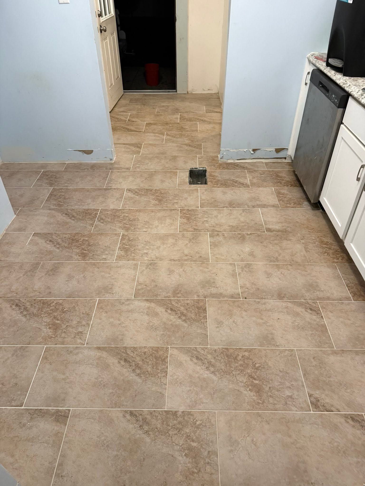 Tiled kitchen floor leading to an open doorway, with cabinets along the right side.