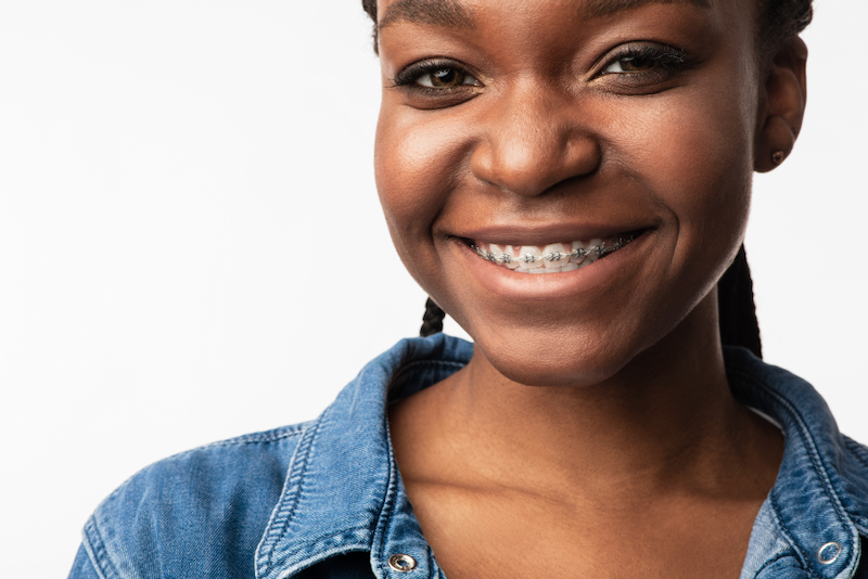 A young woman with braces on her teeth is smiling.