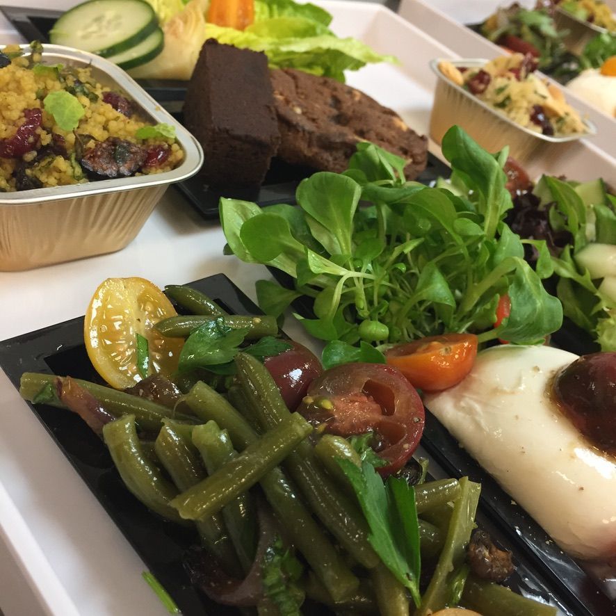 Assorted catered dishes with vegetables, greens, and meat on a buffet table