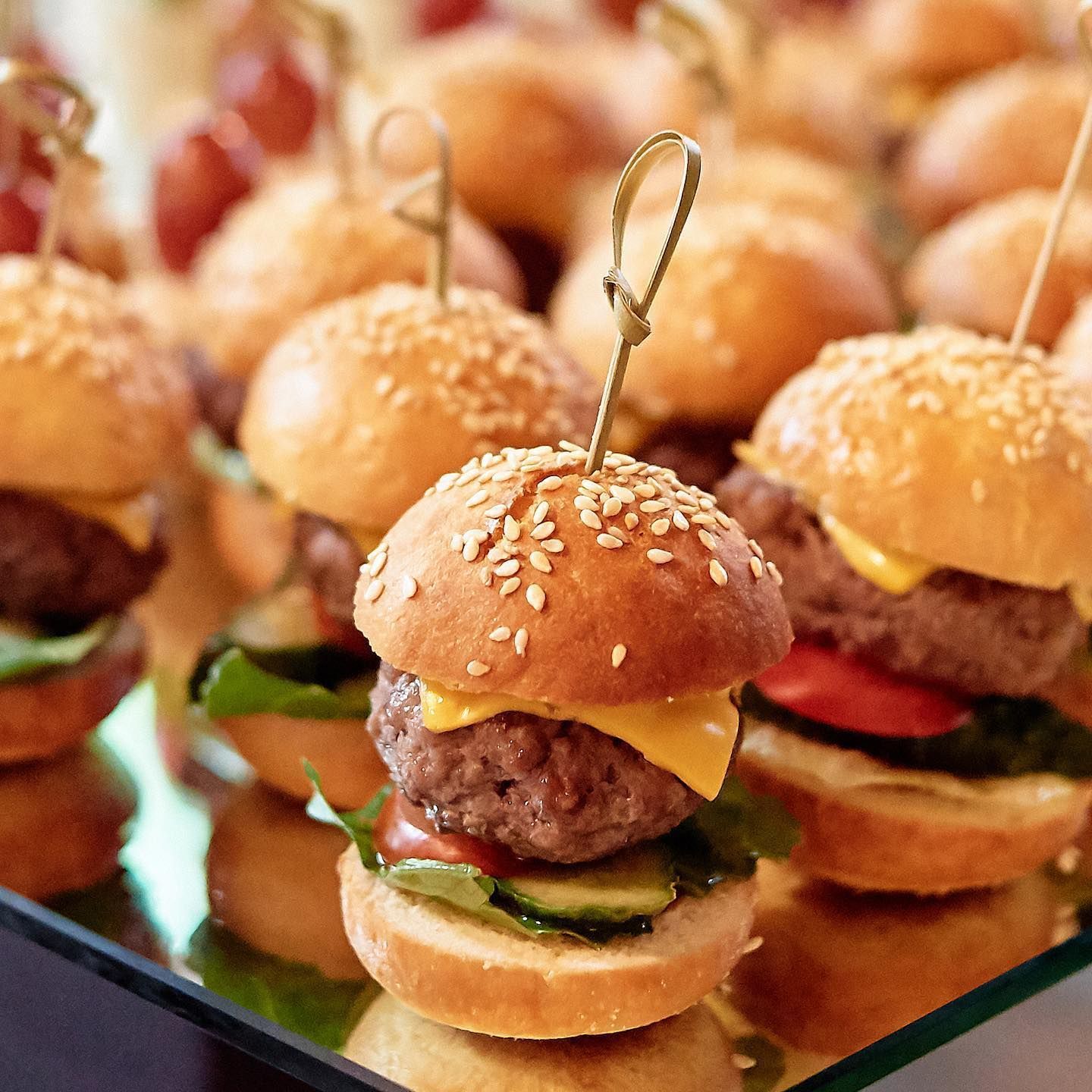 Mini cheeseburger sliders on skewers arranged on a serving tray
