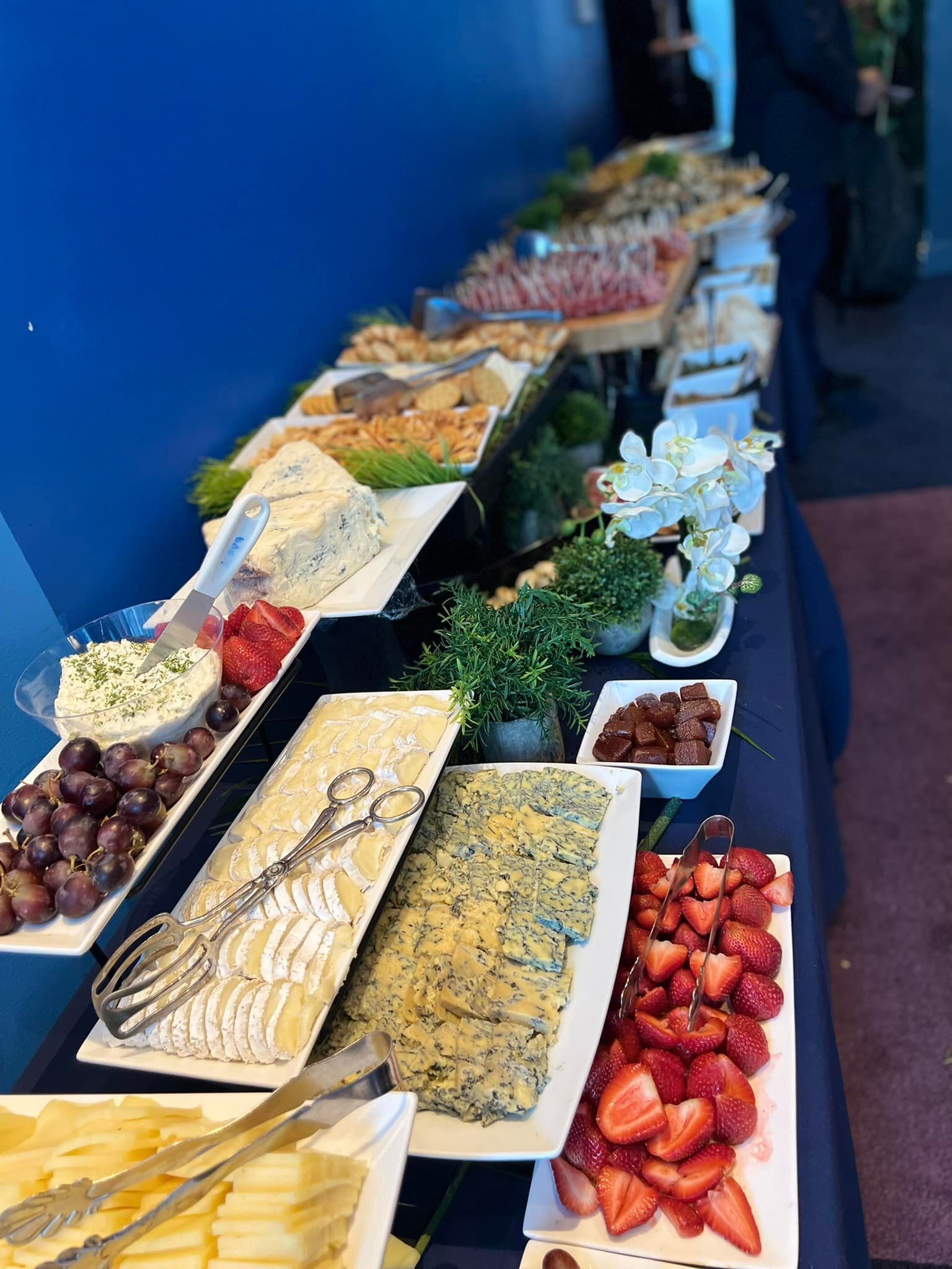 Buffet table with assorted salads, fruits, and desserts in white serving dishes