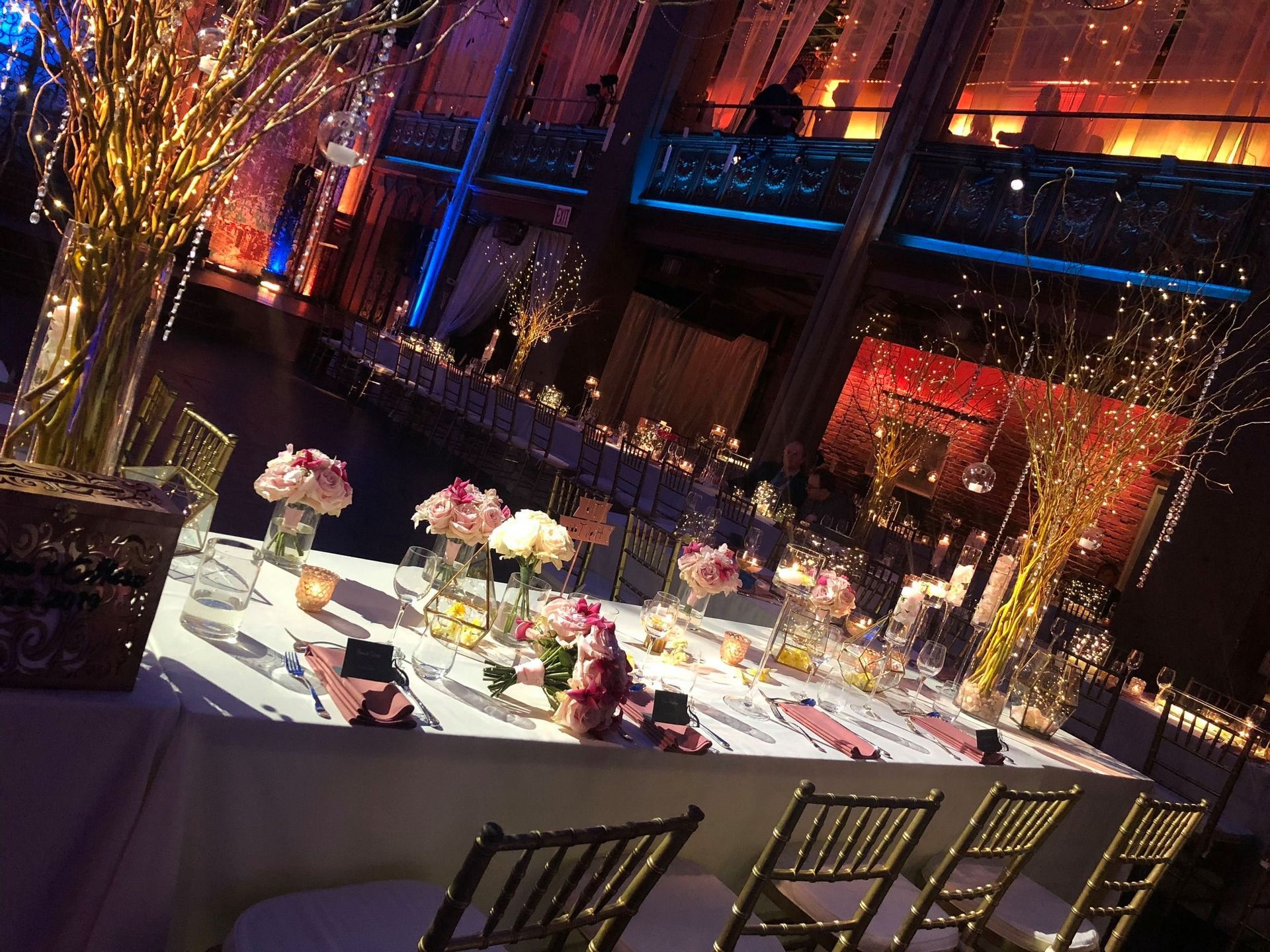 Elegant banquet table set with flowers and candles in a warmly lit, colorful event hall
