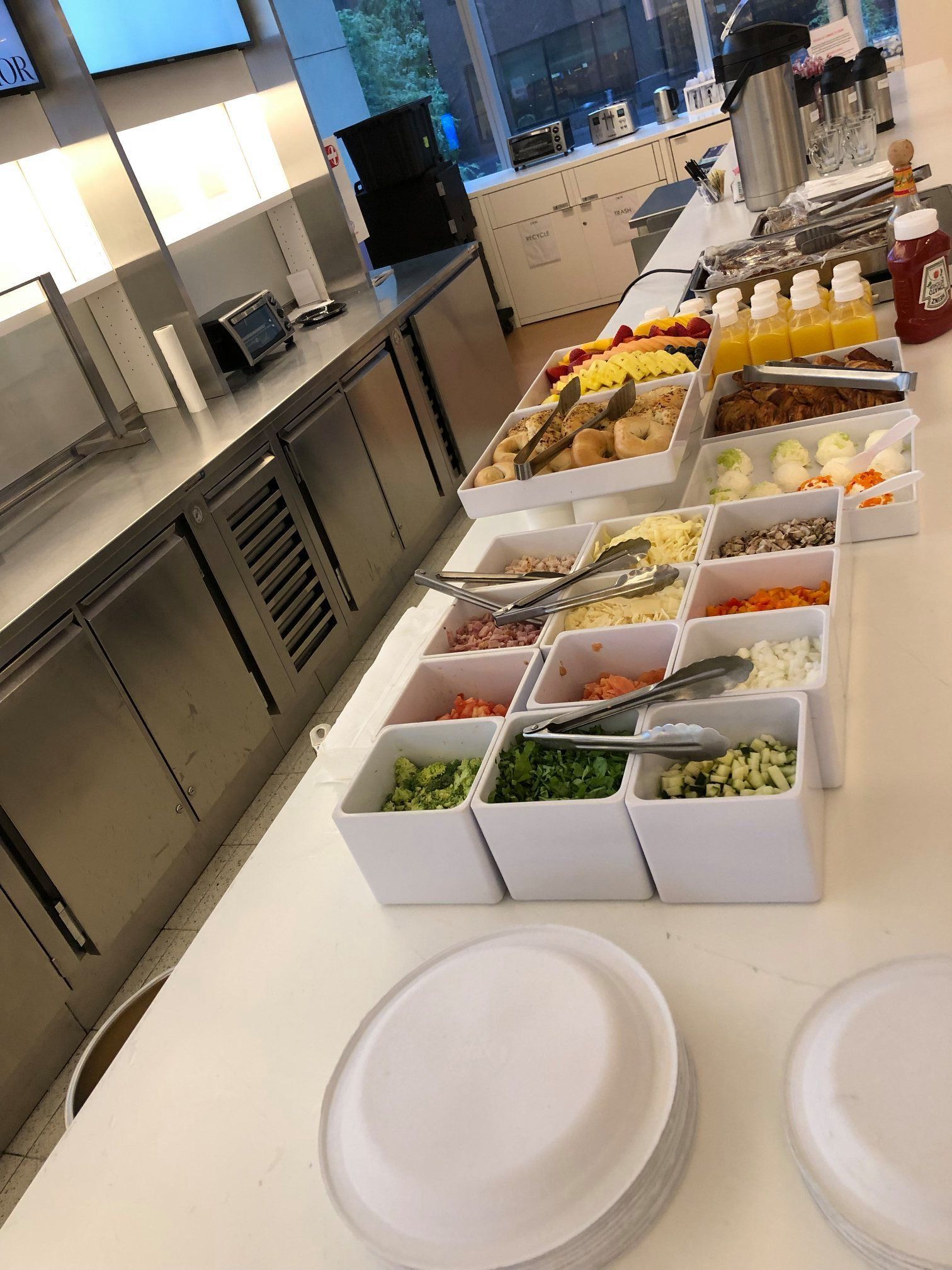 Buffet counter with trays of fruit, salads, and desserts in a cafeteria