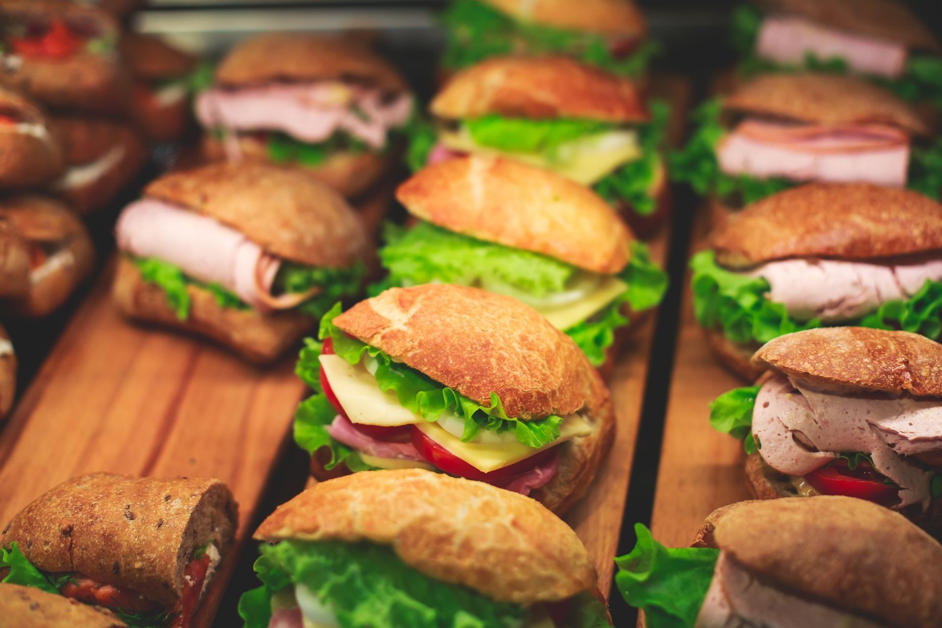 Assorted mini sandwiches and wraps arranged on a wooden board at a buffet table
