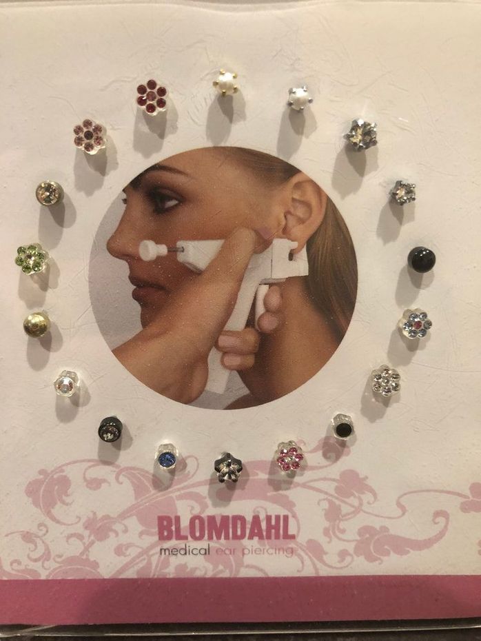 Blomdahl earring display card with multiple stud earrings arranged around a model face photo