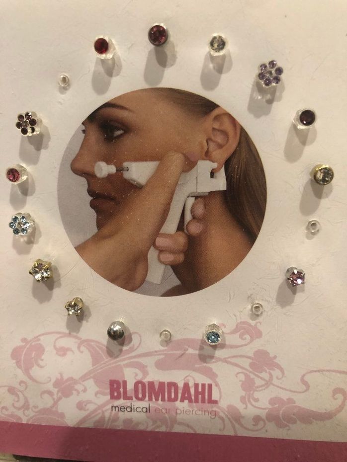 Blomdahl earrings display card with a close-up of an ear being pierced, surrounded by stud earrings