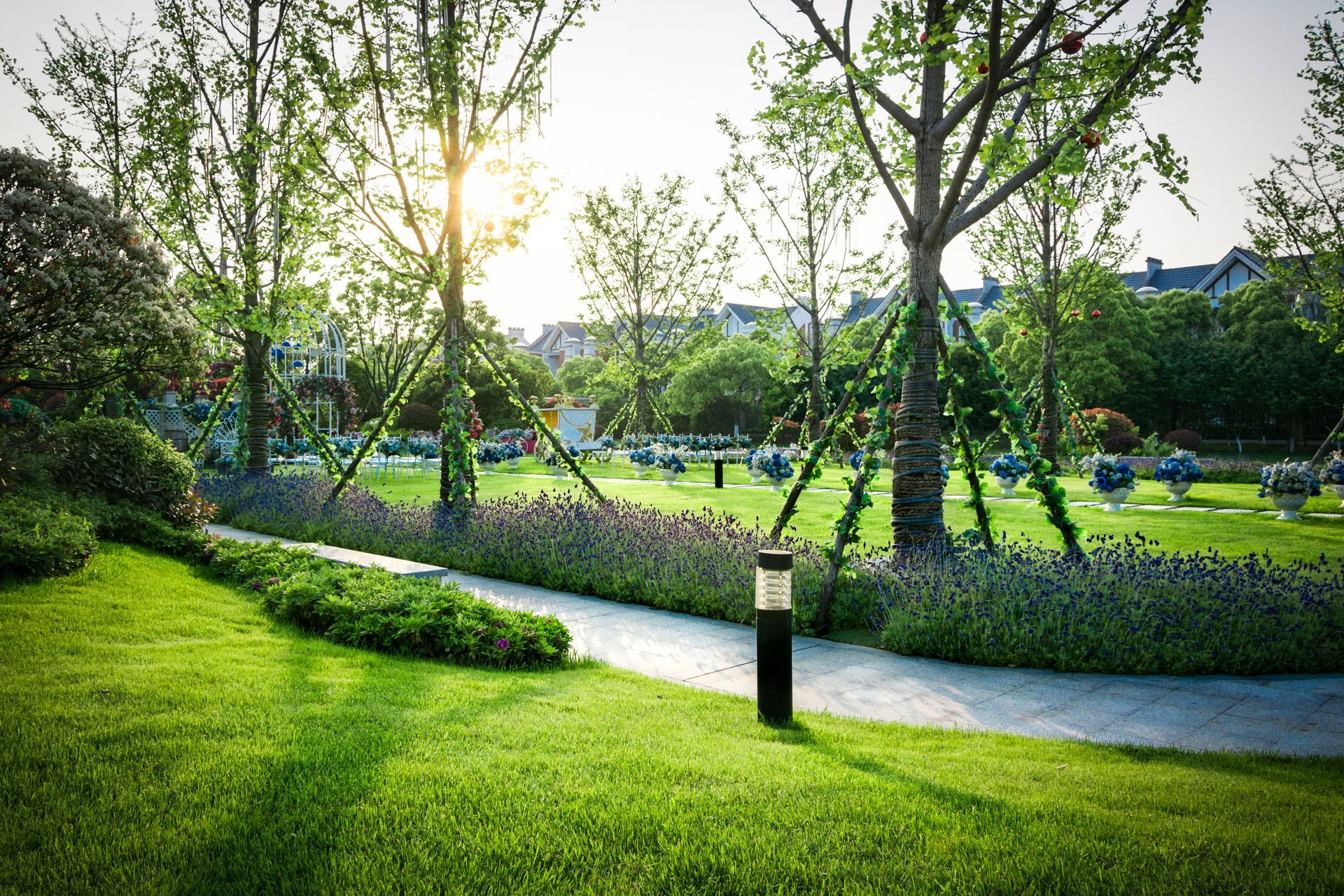 Sunlit park with green lawns, trees, winding path, and people relaxing in the distance