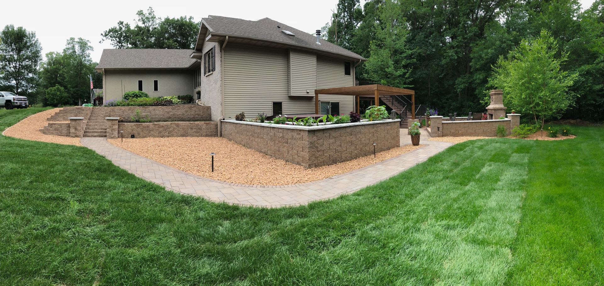 Suburban house with a stone retaining wall, landscaped yard, and green lawn