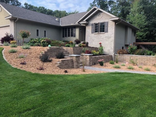 Suburban house with landscaped front yard, stone retaining wall, and green lawn