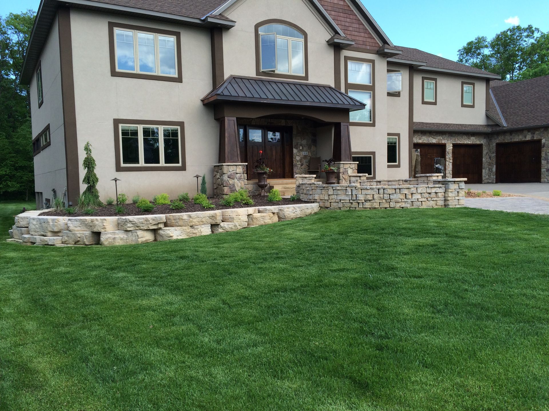 Large two-story suburban house with stone landscaping and a green lawn