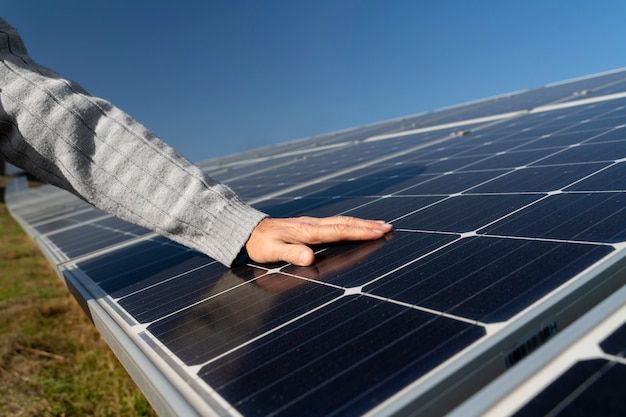 A person is touching a solar panel with their hand.