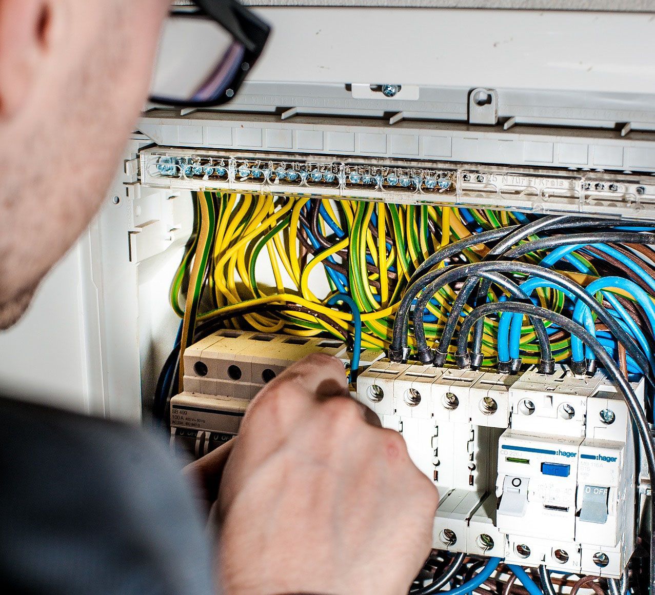 A man is working on an electrical box with a screwdriver.