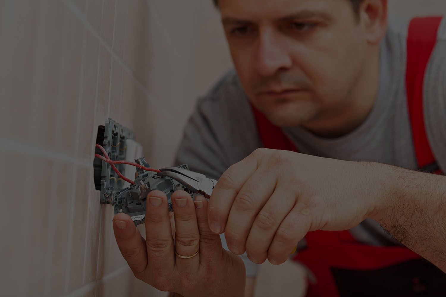 A man is fixing a light switch on a wall.