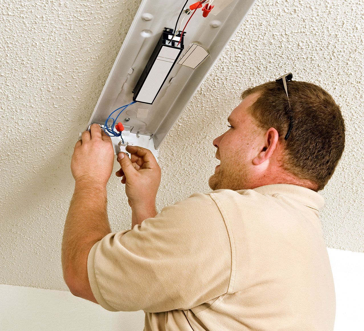 A man is working on a light fixture on the ceiling