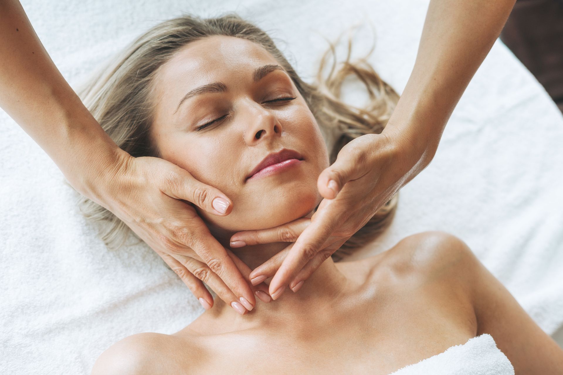 A woman is getting a face massage at a spa.