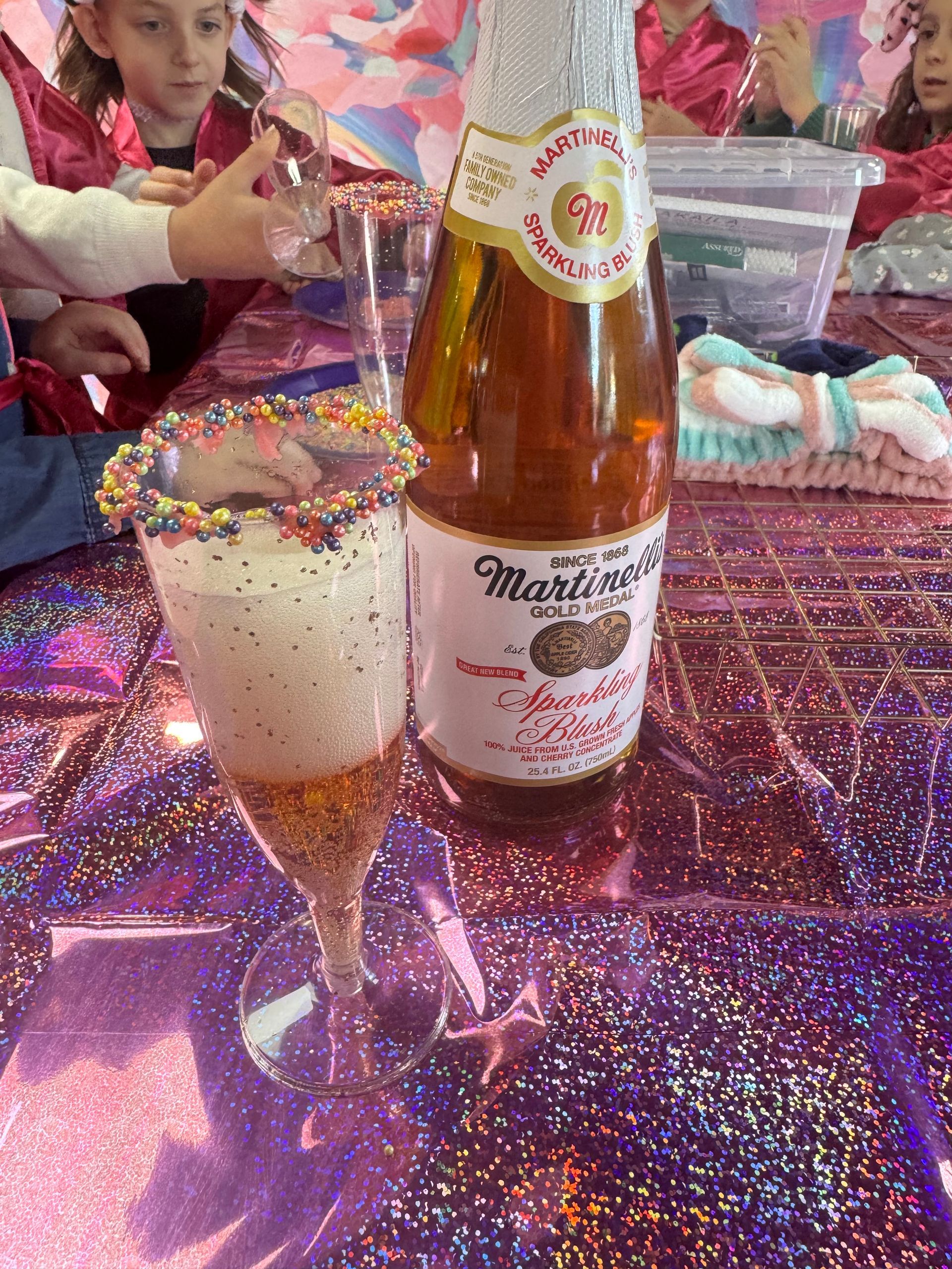 A bottle of martini sparkling wine next to a glass with sprinkles on it.