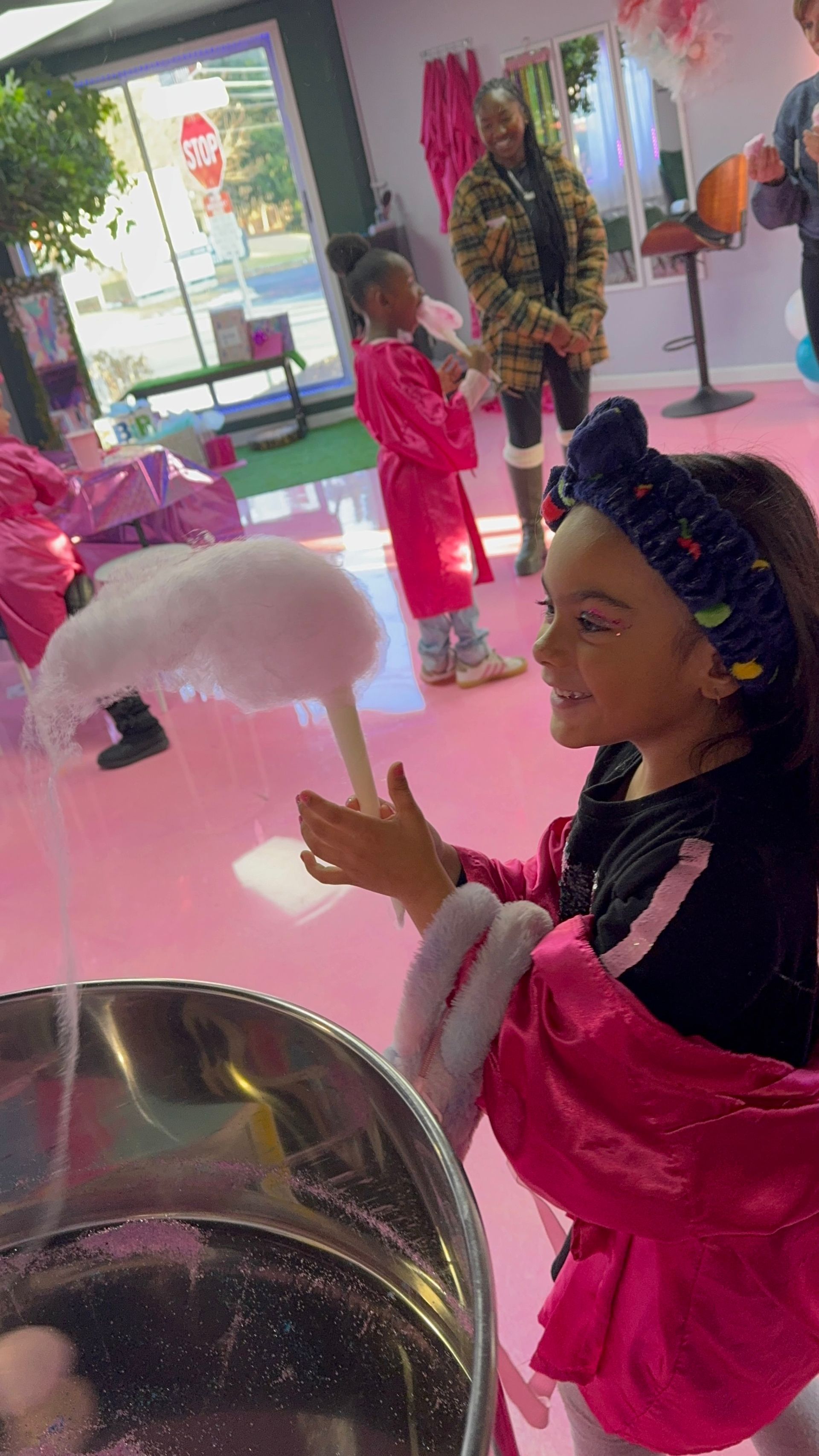 A little girl is playing with cotton candy in a pink room.