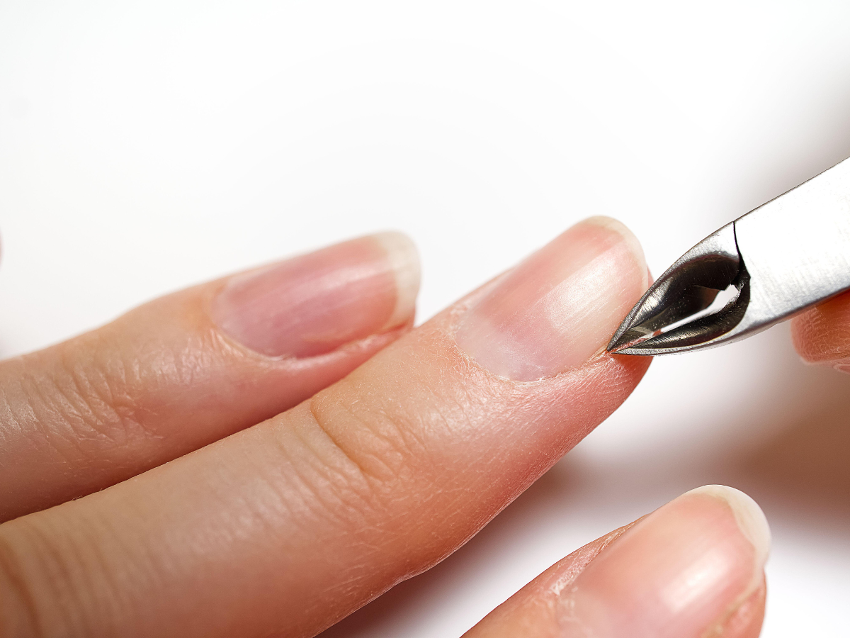 Person trimming cuticle with a nail clipper.
