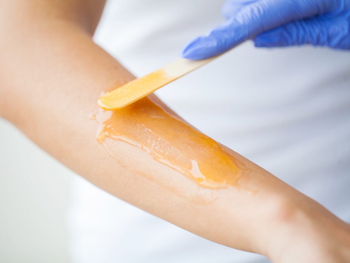 A woman is getting her arm waxed