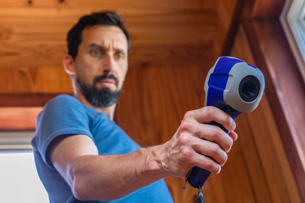 A man is holding a thermometer in his hand in front of a window.