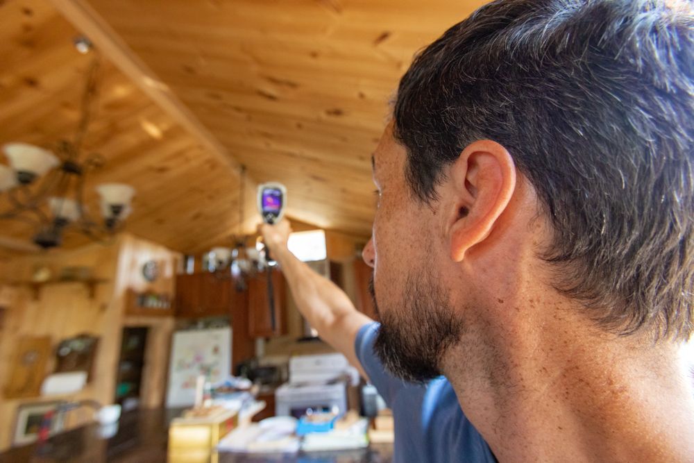 A man is measuring the temperature of a room with a thermometer.