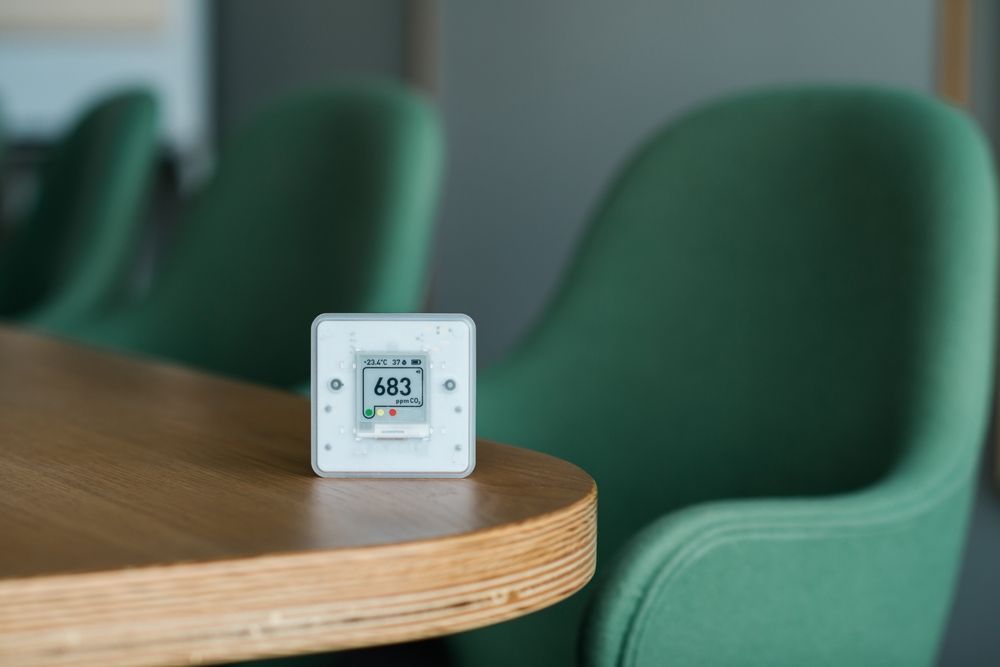 A thermometer is sitting on a wooden table next to a green chair.