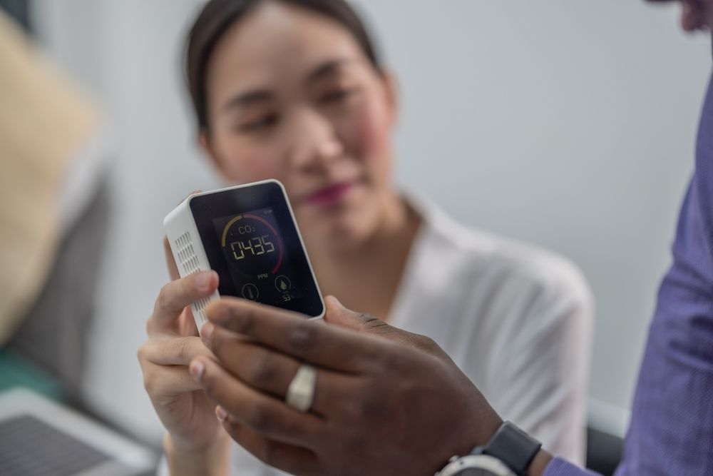A man is holding a cell phone in front of a woman.