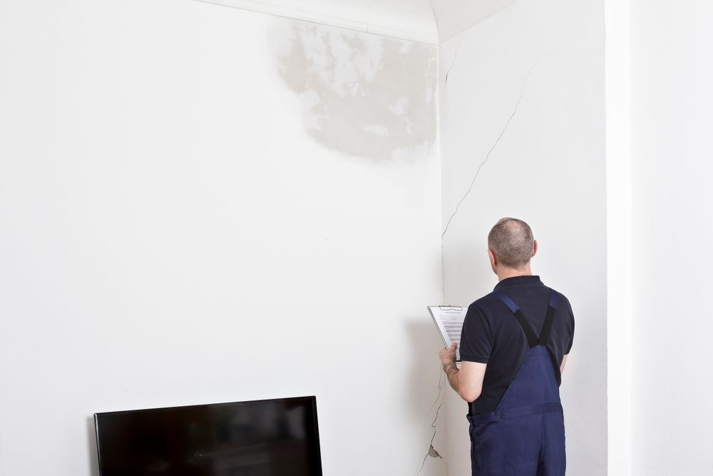 A man is plastering a wall in a living room.