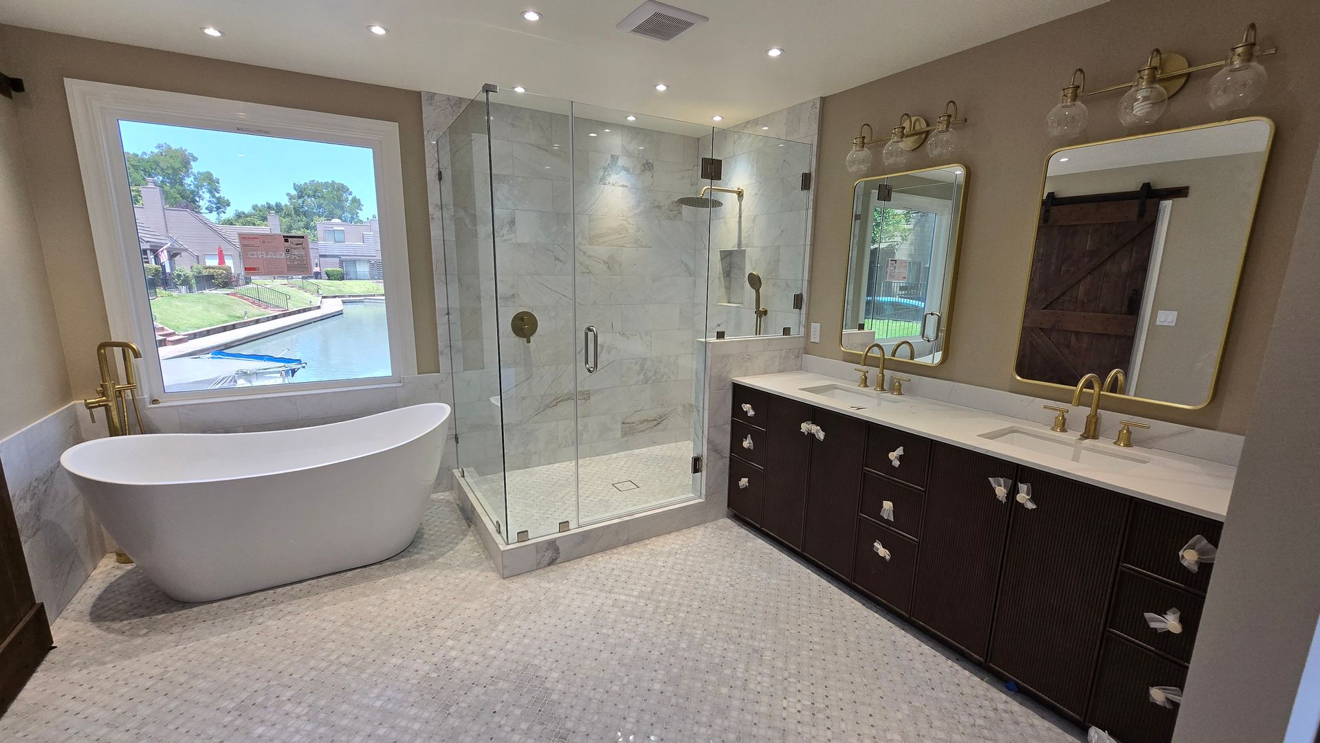 Modern master bathroom featuring a white soaking tub and glass shower.