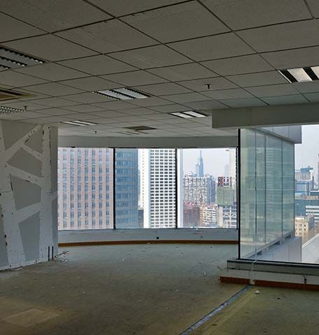 An empty, modern office space with large windows overlooking a city skyline.