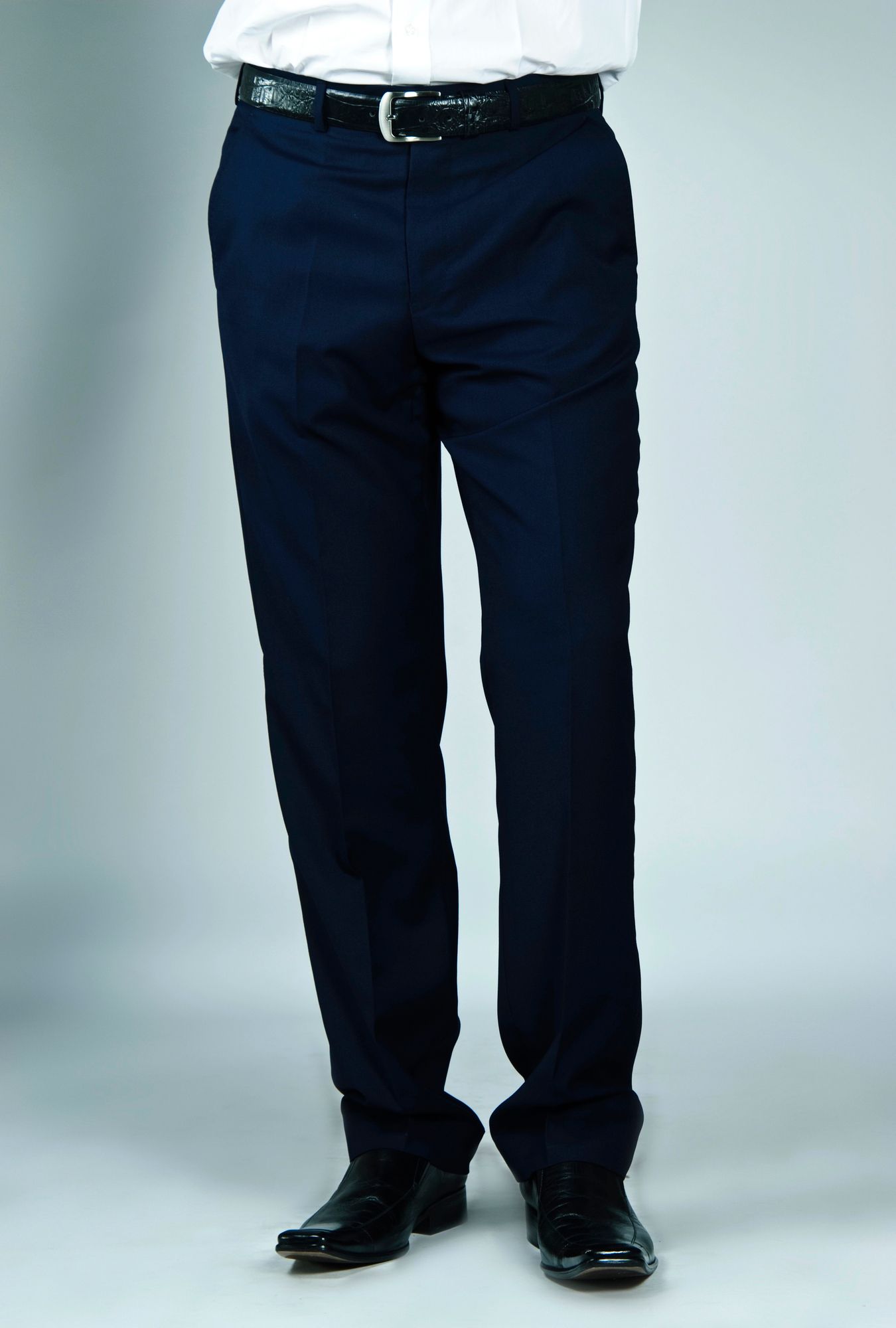 Una persona vestida con pantalones de vestir azul marino, camisa blanca, cinturón negro y zapatos de vestir