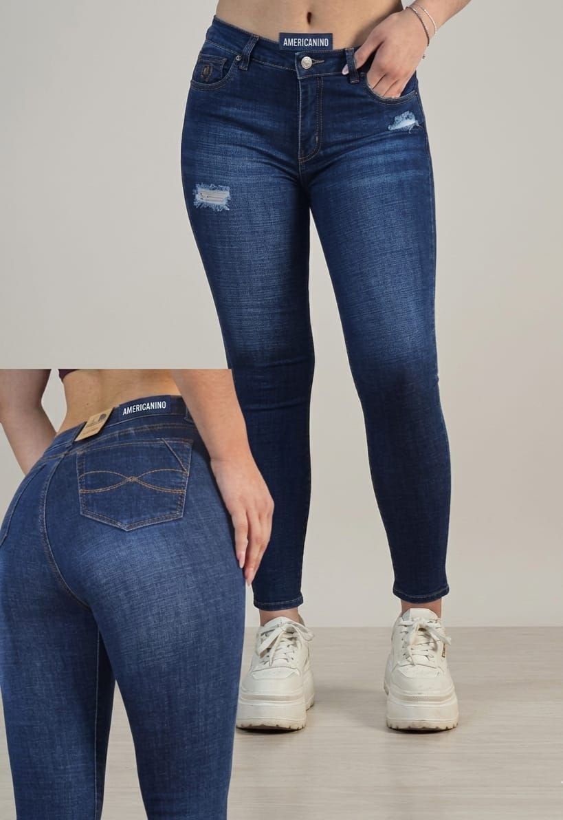 Vista frontal y trasera de unos vaqueros ajustados azul oscuro con zapatillas blancas en una modelo.