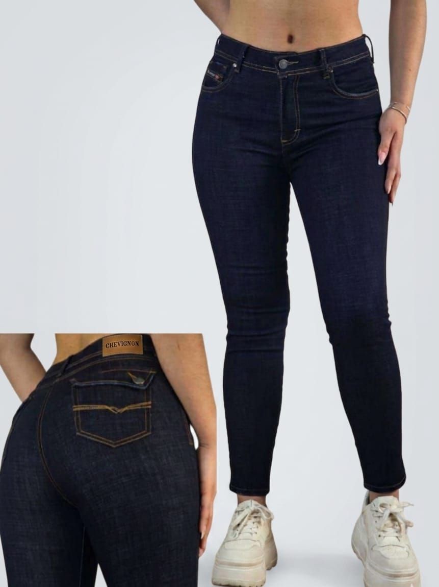 Pantalones vaqueros ajustados de color azul oscuro, mostrados de frente y de espaldas en una modelo con zapatillas blancas.