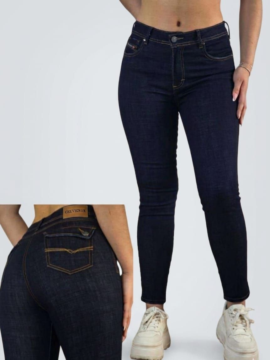 Pantalones vaqueros ajustados de color azul oscuro, mostrados de frente y de espaldas en una modelo con zapatillas blancas.