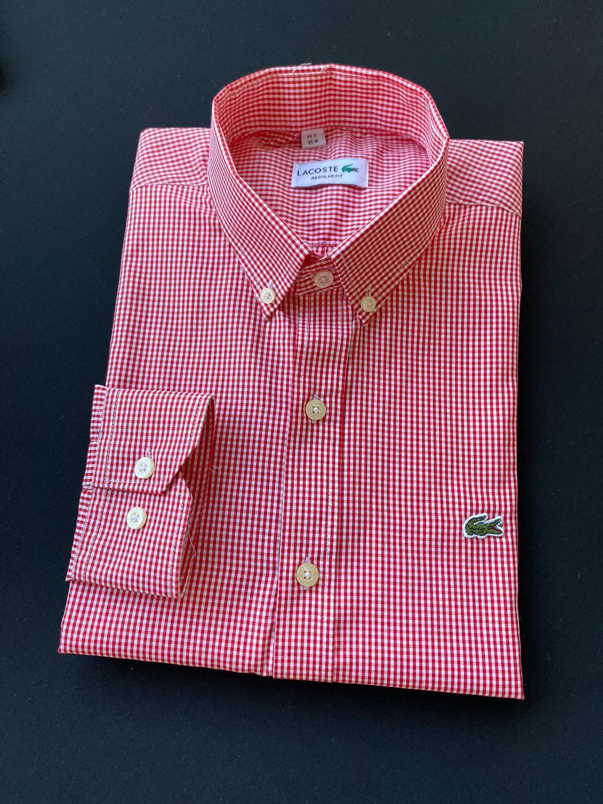 Camisa a cuadros rojos y blancos doblada sobre un fondo oscuro.